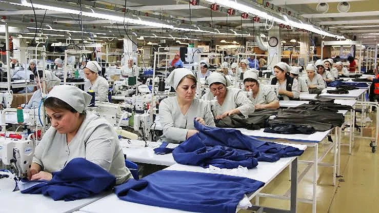 Tekstil sektöründe kadın istihdamı ve çalışma koşulları Tekstil atölyesinde çalışan kadınlar, dikiş makineleri etrafında düzenli bir şekilde çalışıyor.
