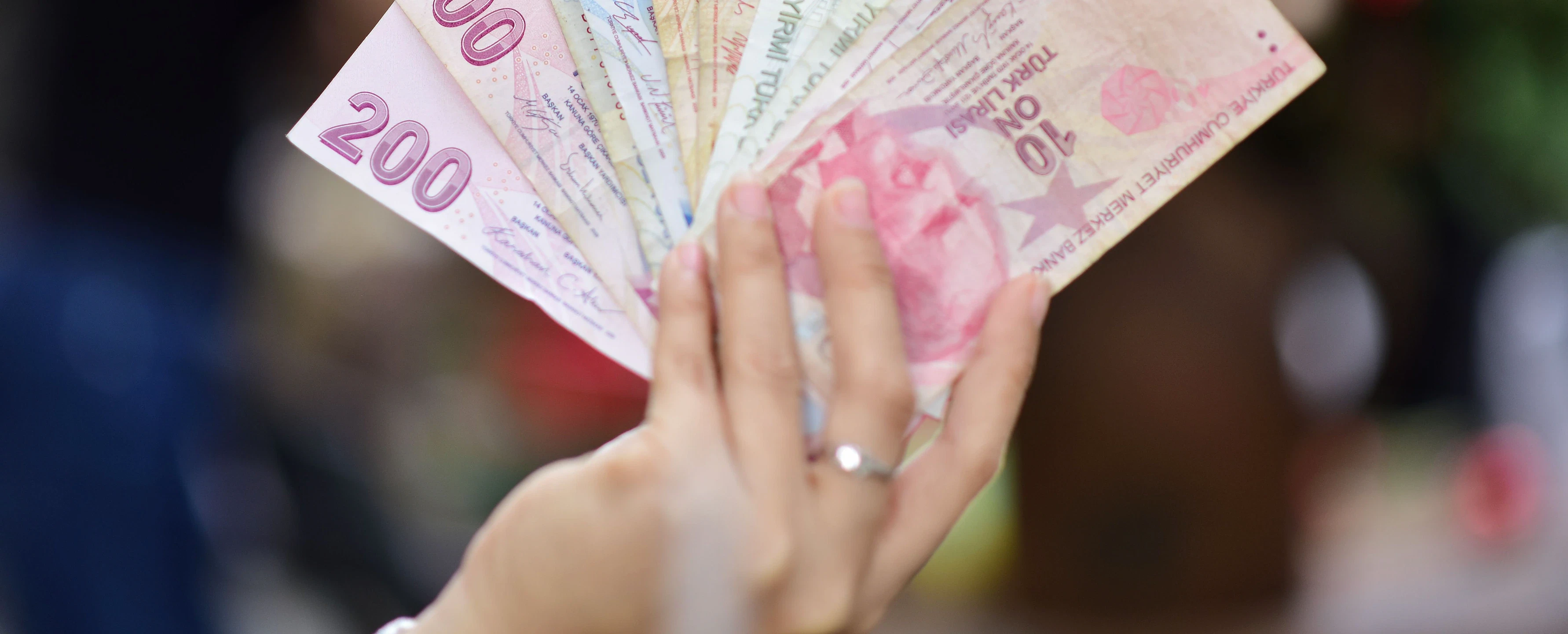 Tekstil sektörü iş ilanları ve fırsatları Çeşitli banknotlarla dolu bir el, tekstil sektörü iş fırsatlarını simgeliyor.
