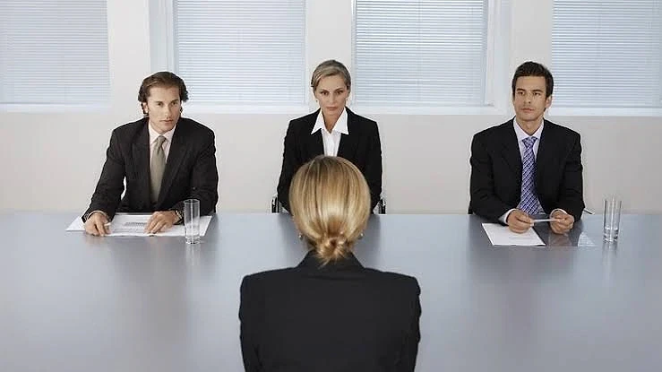 İş görüşmesi sırasında aday ve panel üyeleri Üç profesyonel iş görüşmesi yaparken bir adayın arka görünümü, iş ortamı