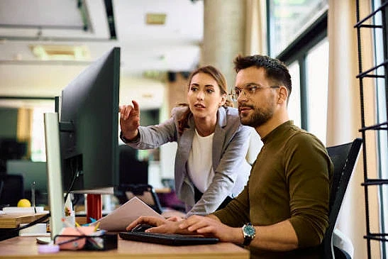 İşverenlerin Aradığı Pozisyonlar 2026 Ofis ortamında bilgisayar başında çalışan bir erkek ve kadın, iş pozisyonları hakkında tartışıyorlar.