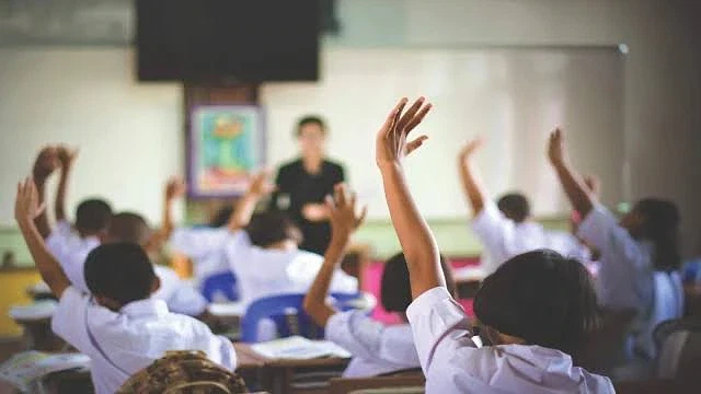 Öğretmenlik mesleği ve görevleri hakkında bilgi Sınıfta öğretmene yönelen öğrencilerin elleri havada, öğrenme isteği belirgin.