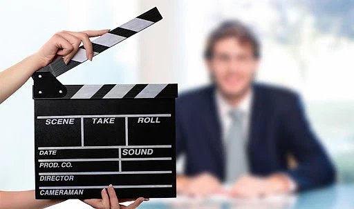 Video CV avantajları ve dikkat edilmesi gerekenler Video CV hazırlığı için kullanılan clapperboard ve arka planda iş görüşmesi yapan bir kişi.
