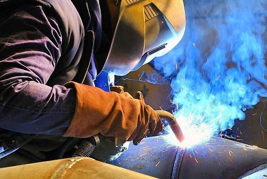 Kaynak işlemleri ve güvenlik önlemleri Kaynak işlemi yapan işçi, koruyucu ekipmanla metal üzerinde çalışıyor.