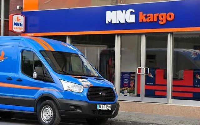 MNG Kargo maaşları hakkında detaylı bilgi MNG Kargo şubesinin önünde mavi bir kargo aracı, işletmenin logosu görünmekte.