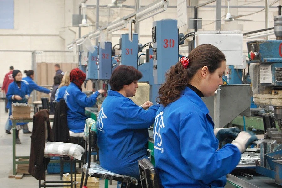 Yüksek maaşlı vardiyalı meslekler 2026 Vardiyalı iş ortamında çalışan bireyler, mavi iş kıyafetleriyle üretim yapıyor