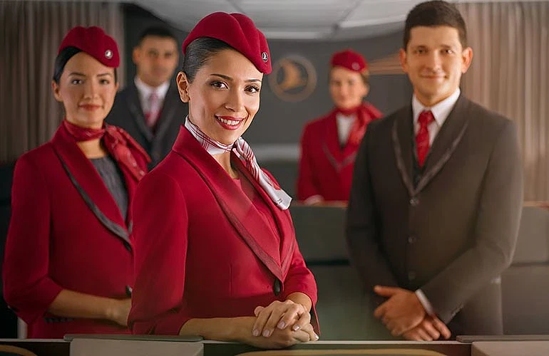Hosteslik ve hostluk mesleği hakkında bilgi Hostes ve hostların görev yaptığı bir uçak kabininde gülümseyen profesyonel ekip.