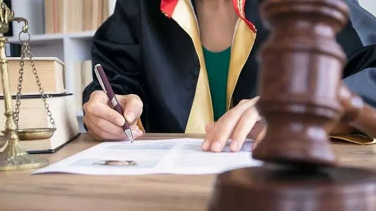 2026 Avukat Maaşları ve Gelir Analizi Hukuk bürosunda belgeleri imzalayan avukat, yanında terazi ve mahkeme tokmağı var.