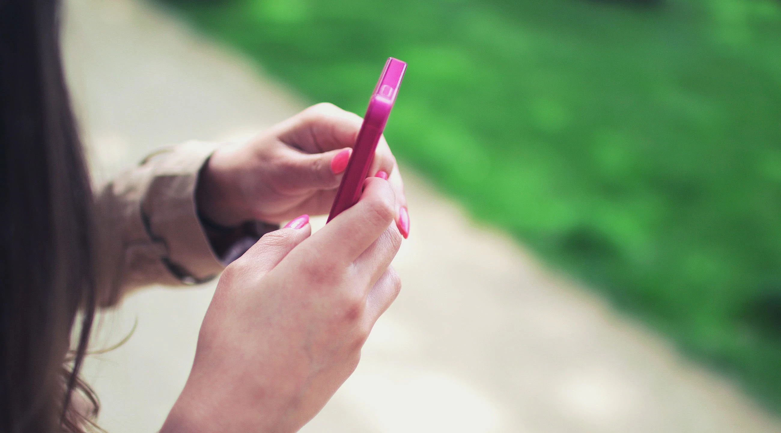 Engelli maaşı ve başvuru şartları hakkında bilgi Bir kadının elinde pembe bir telefon tutarak dışarıda durduğu bir an.