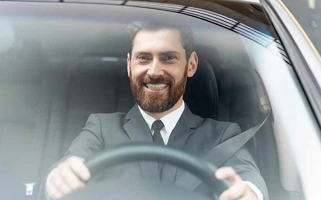 2026 şoför maaşları hakkında bilgi veriyor Koltukta oturan şoför, direksiyonu tutarak gülümsemekte.